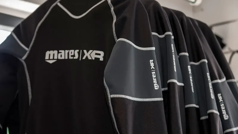 Combinaisons de plongée noires Mares XR suspendues en rangée, équipement