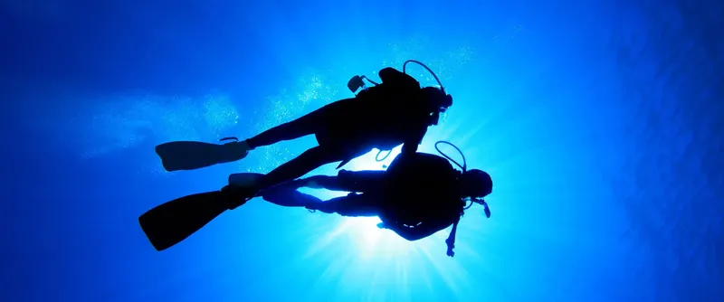 Deux plongeurs en silhouette explorent les profondeurs bleues de l'océan