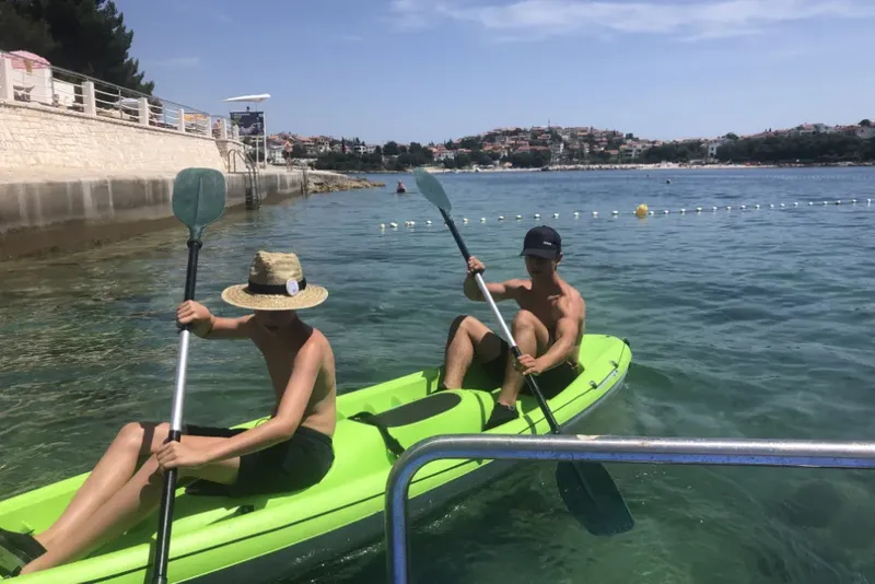 Deux personnes pagayent en kayak sur une eau turquoise claire