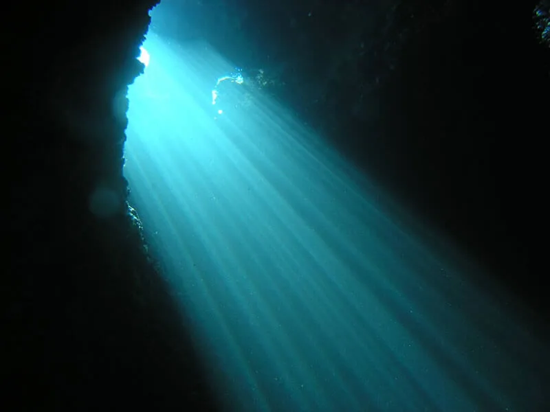 Rayons de soleil perçant l'eau d'une grotte sous-marine sombre