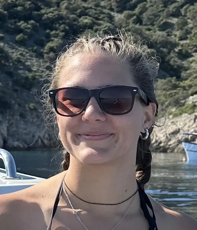Jeune femme souriante portant des lunettes de soleil sur un bateau