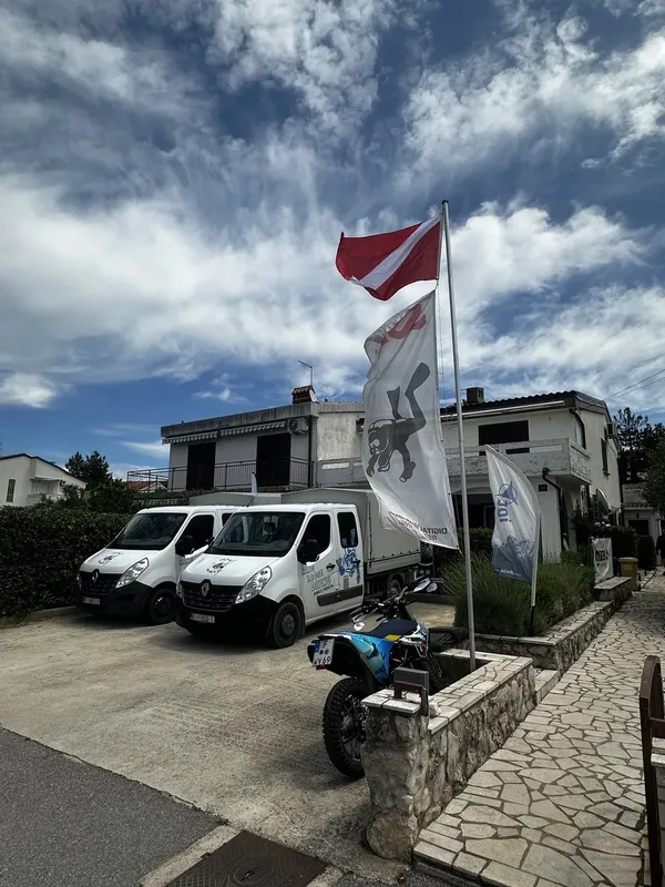 Bâtiment blanc avec drapeau de plongée et fourgonnettes garées devant