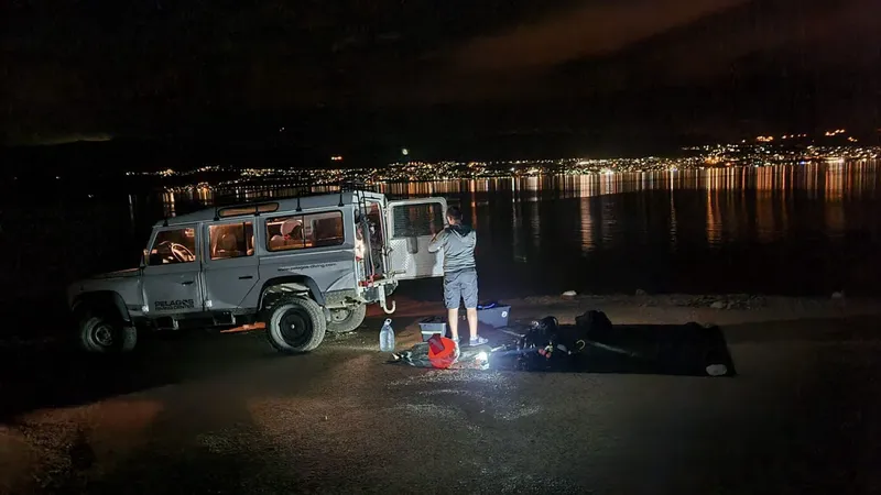 Homme préparant du matériel de plongée près d'un véhicule et de la mer