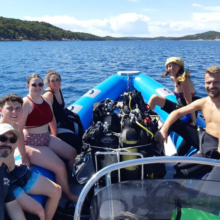 Groupe de plongeurs souriants à bord d'un bateau semi-rigide bleu