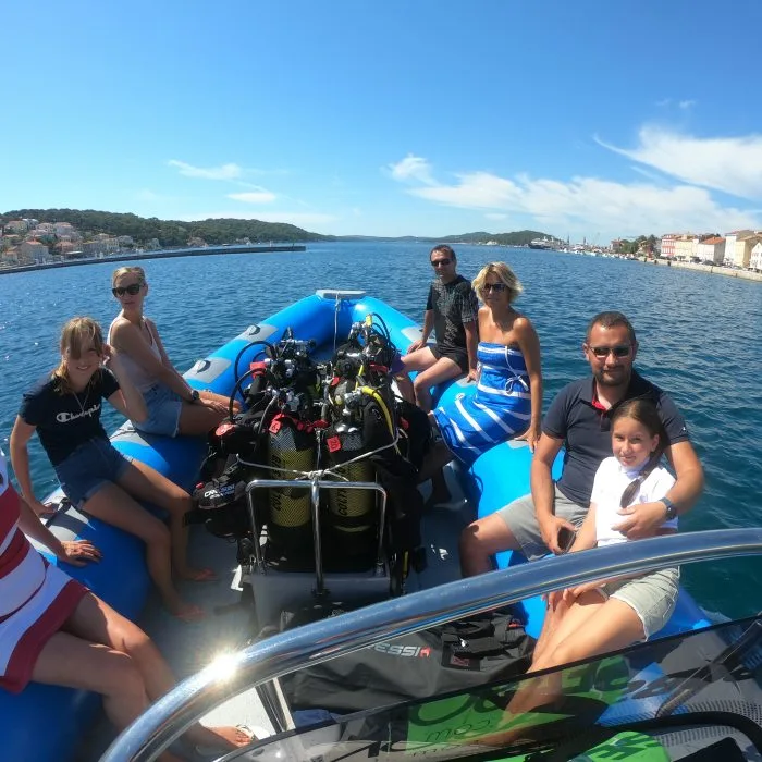 Groupe de personnes souriantes à bord d'un bateau de plongée bleu