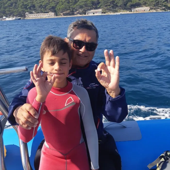 Deux personnes en combinaison de plongée sourient sur un bateau