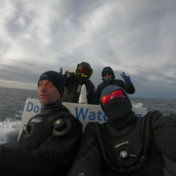 Plongeurs en combinaison sur un bateau semi-rigide, ciel nuageux
