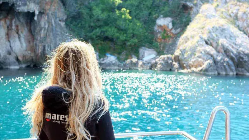 Dos d'une plongeuse regardant un paysage rocheux depuis un bateau