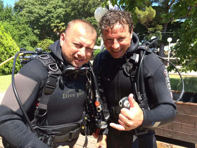 Deux plongeurs souriants équipés prêts pour une immersion en mer