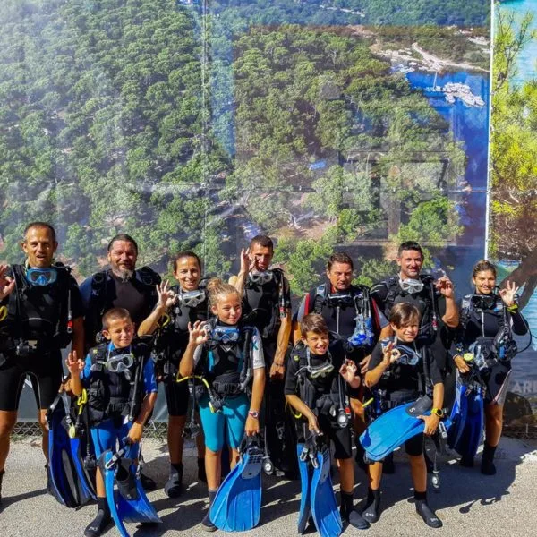 Groupe de plongeurs souriants équipés devant un décor de paysage marin
