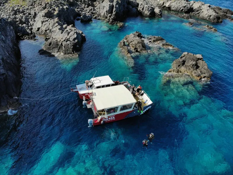 Bateau de plongée au large d'une côte rocheuse avec des plongeurs