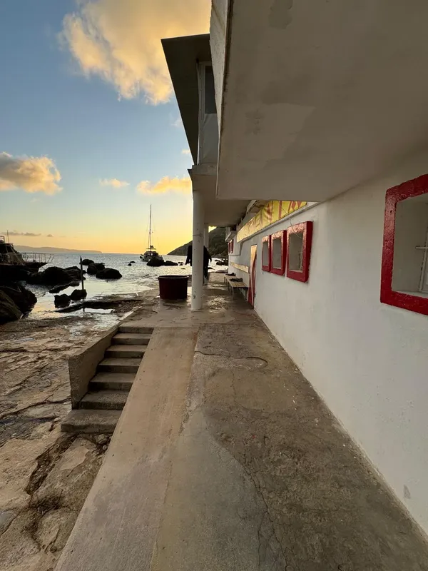 Bâtiment blanc avec escaliers menant à la mer et voiliers au loin