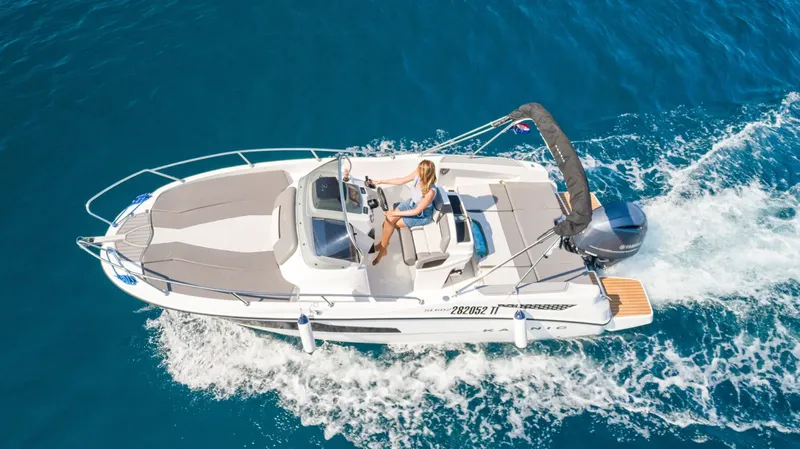 Une femme conduit un bateau rapide sur une mer bleue claire