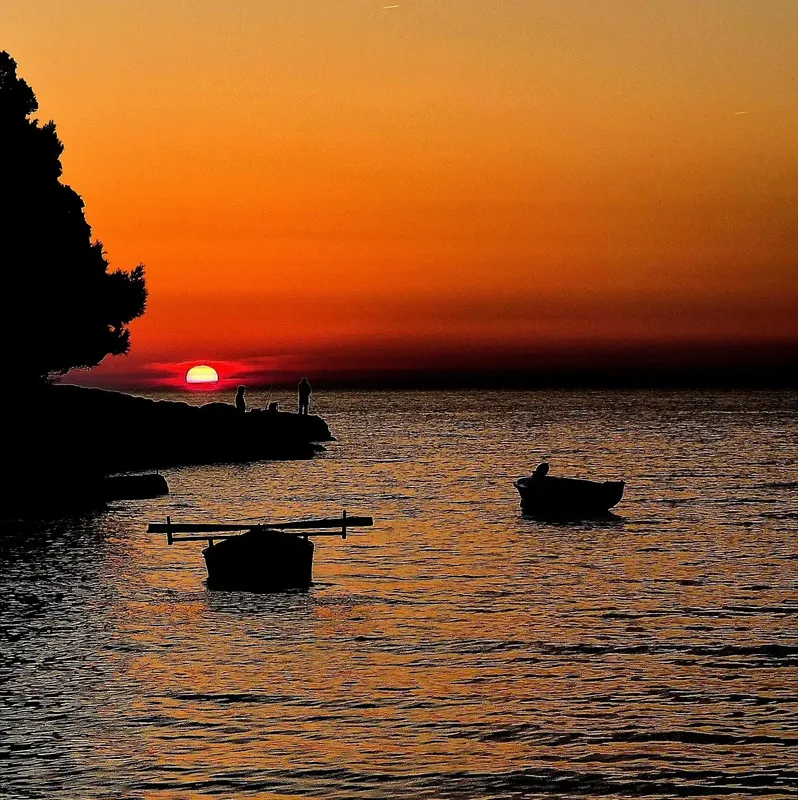 Coucher de soleil sur la mer avec silhouettes de personnes et bateaux