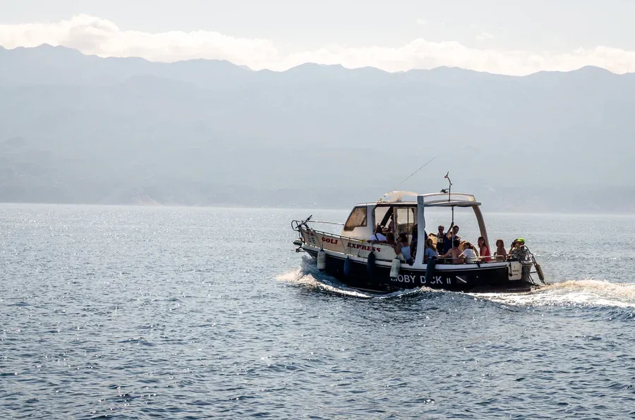 Bateau de plongée en mer avec des passagers, paysage montagneux en arrière-plan