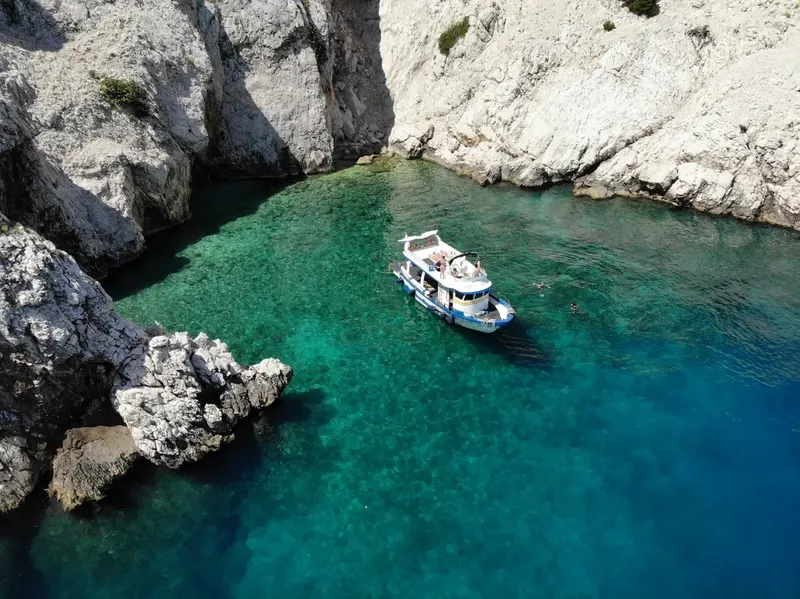 Bateau de plongée amarré dans une crique turquoise rocheuse ensoleillée