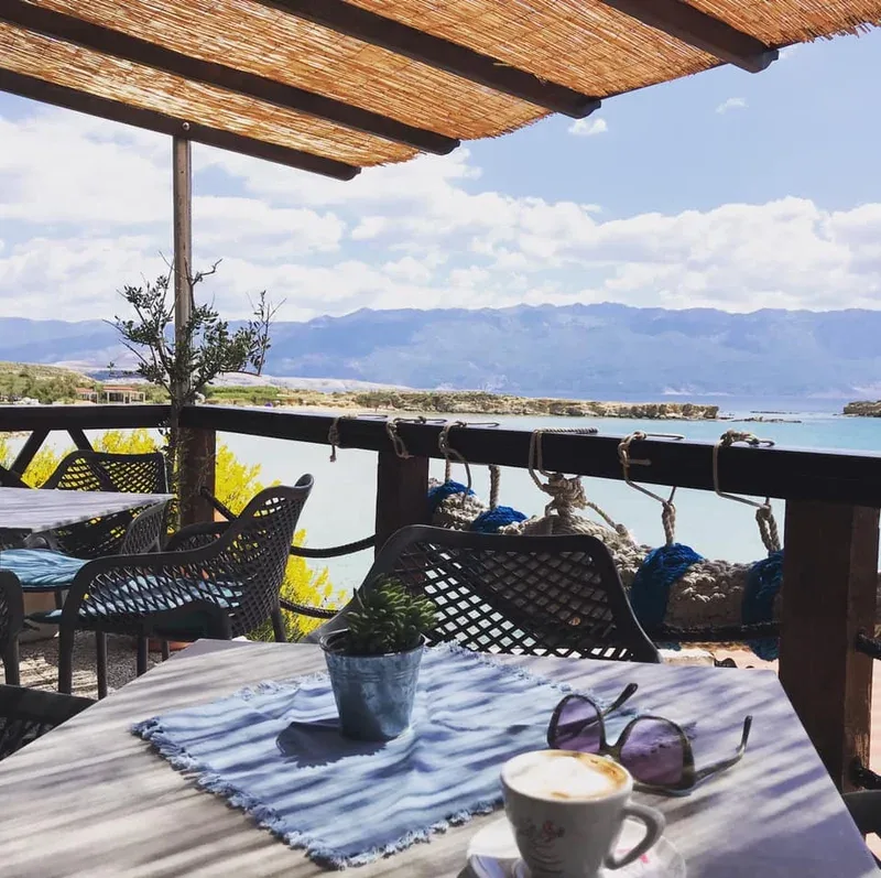 Terrasse ombragée avec vue sur la mer, une tasse de café et des lunettes