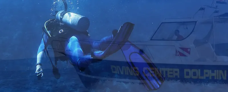 Plongeur explorant les fonds marins près d'un bateau de plongée bleu