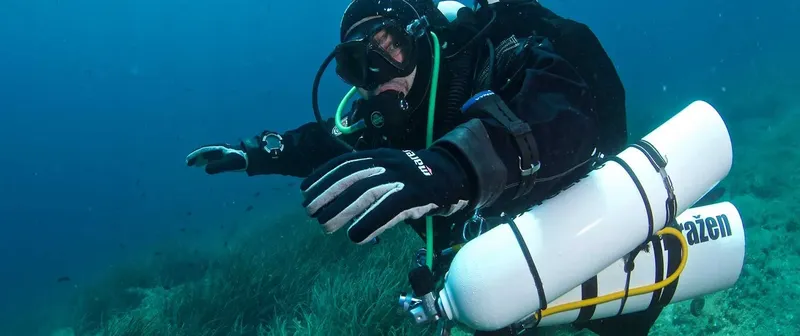 Plongeur en combinaison noire nageant sous l'eau avec son équipement