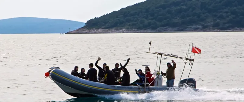 Groupe de plongeurs sur un bateau semi-rigide en mer, souriants