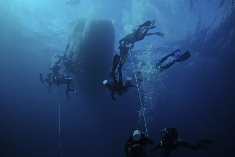 Groupe de plongeurs explorant une épave sous-marine en bleu profond