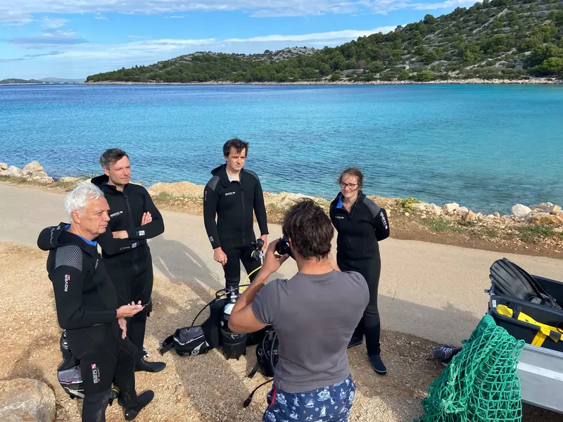 Groupe de plongeurs en combinaison sur un quai ensoleillé