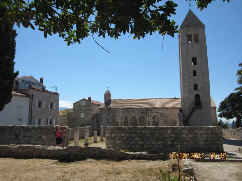 Eglise en pierre avec clocher et quelques personnes devant l'entrée