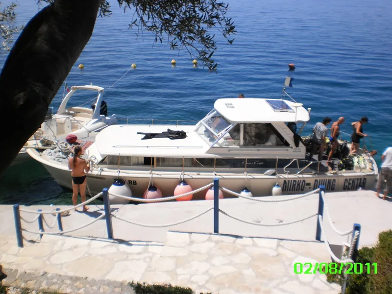Bateau de plongée amarré à un ponton avec des personnes à bord