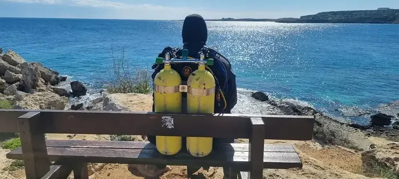 Plongeur assis sur un banc, vue sur la mer et le ciel bleu