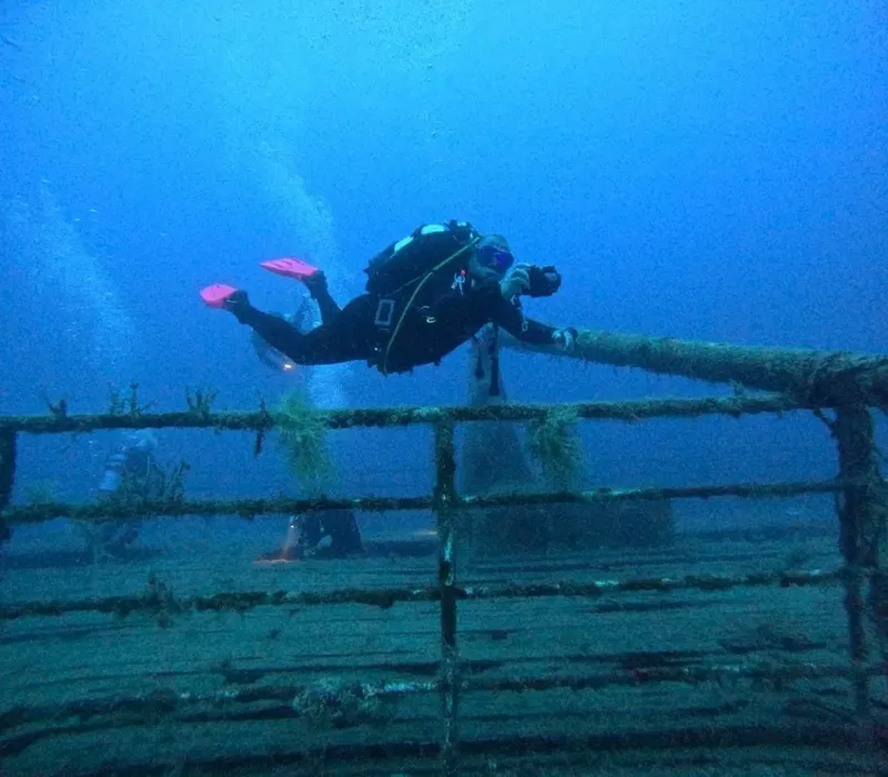 Deux plongeurs explorent une épave métallique sous l'eau