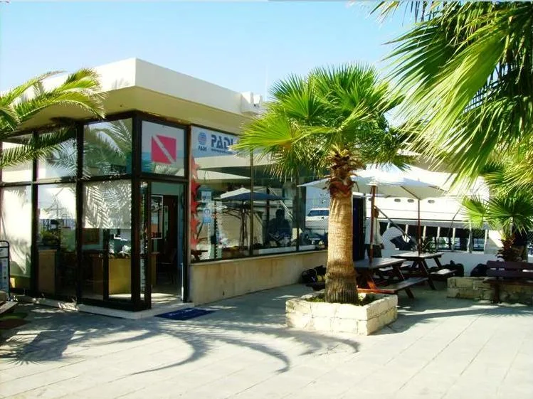 Façade d'un centre de plongée avec bateau amarré et palmiers
