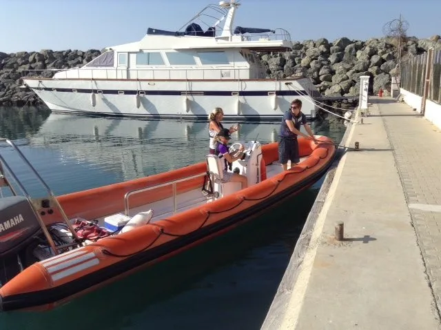 Personnes sur un bateau semi-rigide orange amarré à un quai