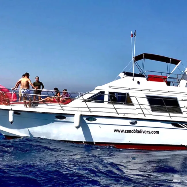 Bateau de plongée blanc et rouge avec des personnes à bord en mer