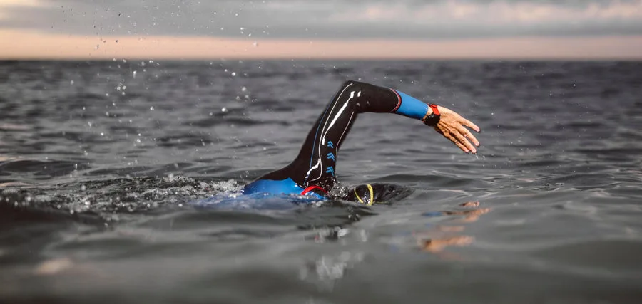 Nageur en pleine mer, style crawl, combinaison de natation bleue et noire