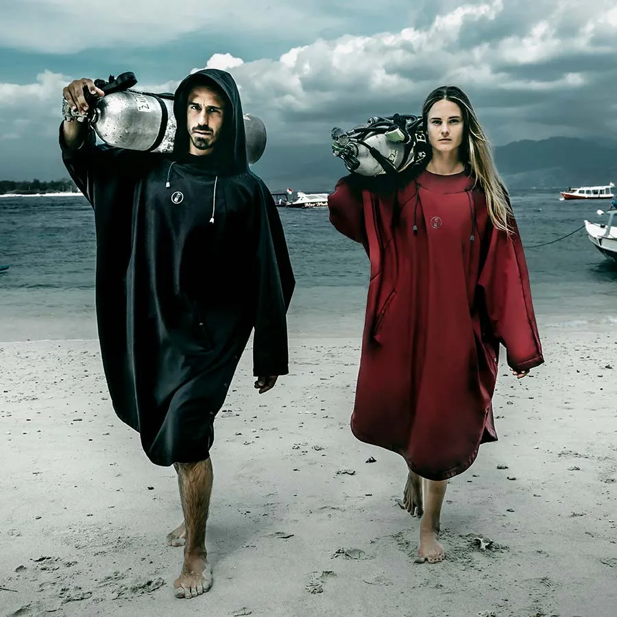 Deux plongeurs marchant sur une plage avec leurs bouteilles