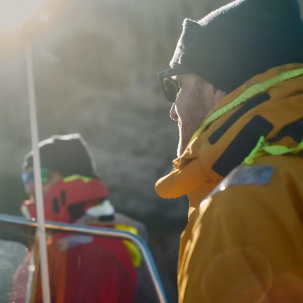 Deux personnes en veste jaune et rouge regardent vers l'horizon en mer