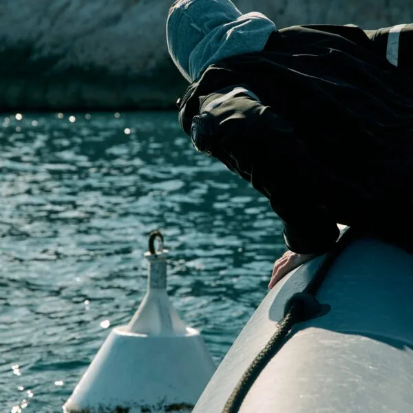 Personne regardant l'eau depuis un bateau, ciel gris, mer calme