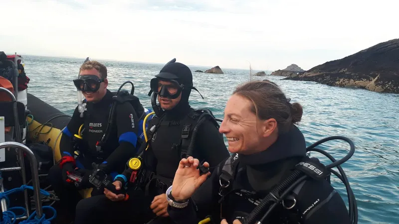 Trois plongeurs souriants en combinaison sur un bateau en mer