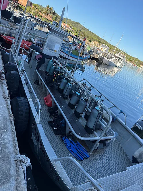 Bateau de plongée amarré avec des bouteilles et palmes à bord