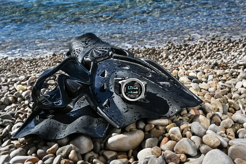 Masque et ordinateur de plongée noirs sur un lit de galets