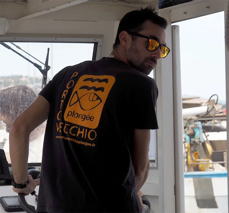 Homme portant un t-shirt avec un logo de plongée sur un bateau