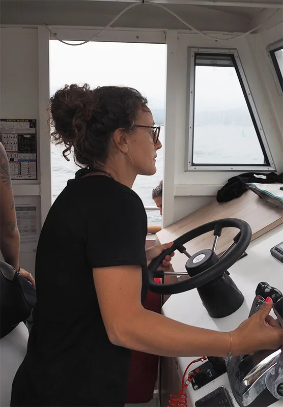 Femme conduisant un bateau de plongée, vue de profil, en mer