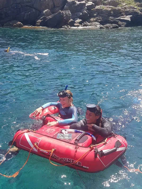 Deux plongeurs souriants sur un petit bateau rouge en mer