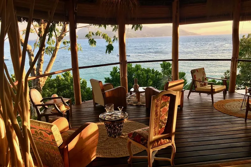 Terrasse en bois avec mobilier, vue sur la mer et végétation luxuriante