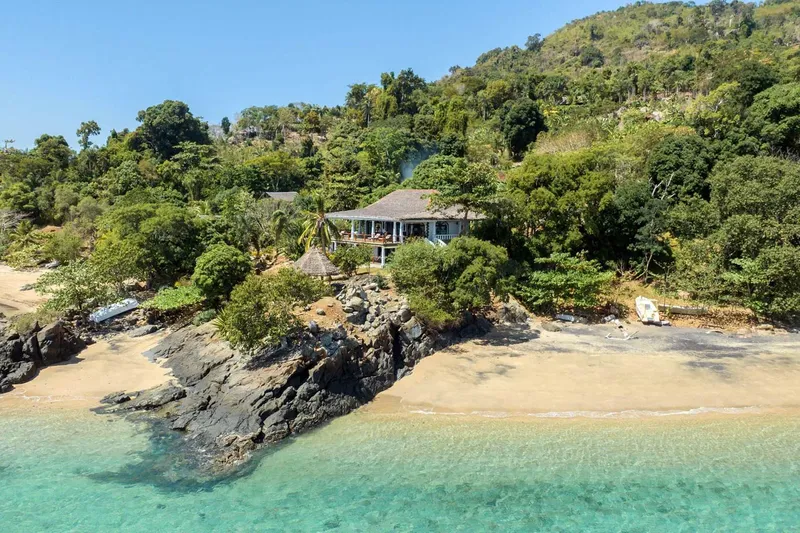 Vue aérienne d'une plage avec des bâtiments et végétation luxuriante