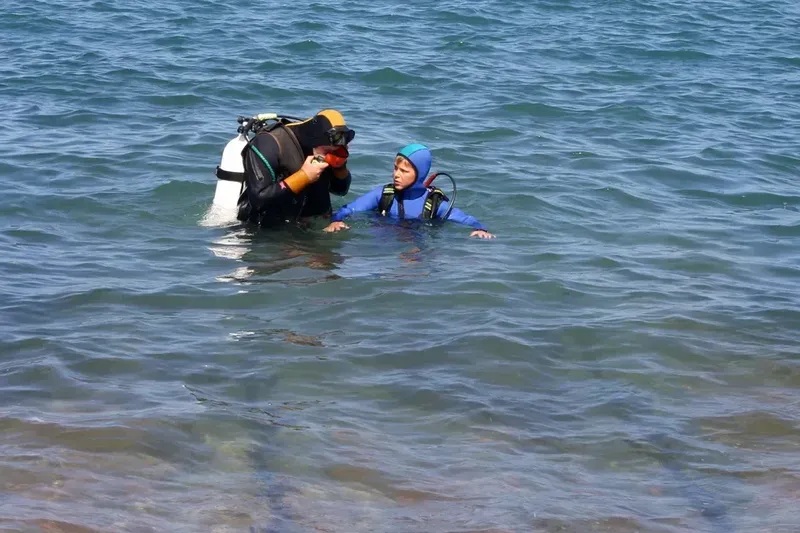 Moniteur de plongée aide un élève à mettre son masque en mer