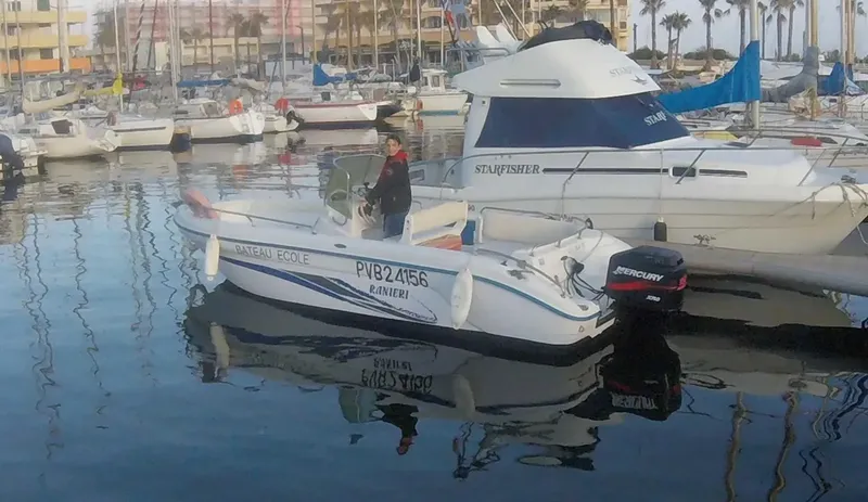 Un homme se tient debout sur un bateau blanc amarré au port