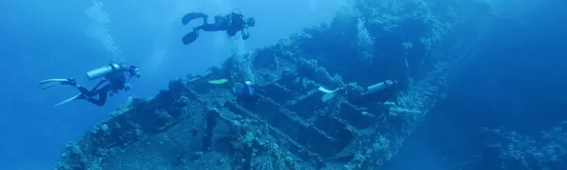 Plongeurs explorant l'épave d'un navire sous l'eau bleu profond