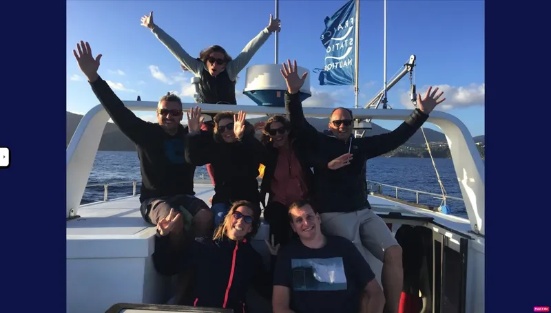 Groupe de personnes souriantes et levant les bras sur un bateau
