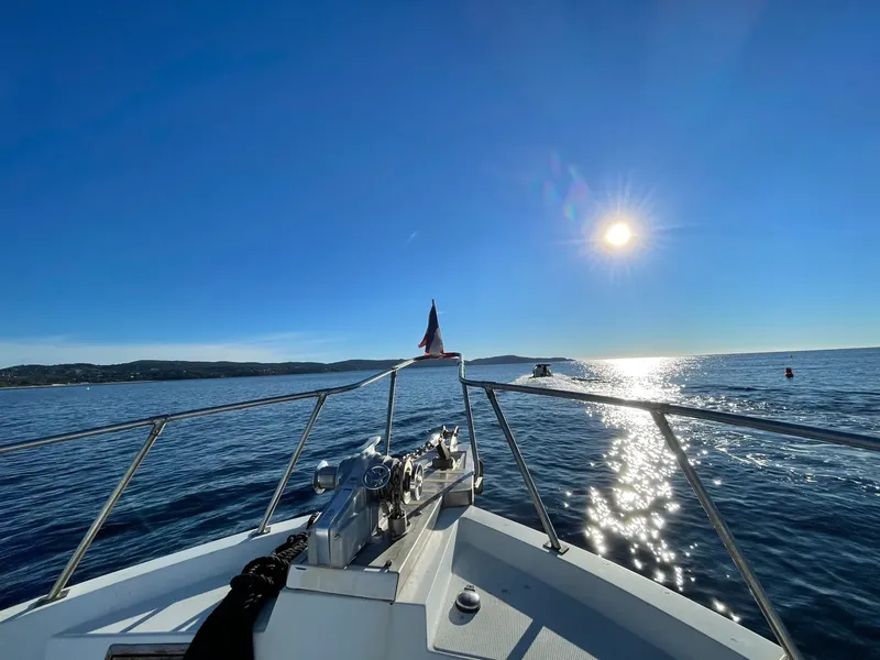 Bateau de plongée naviguant sur une mer ensoleillée et scintillante